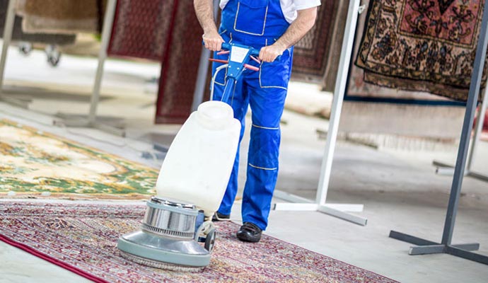 A worker cleaning the rug