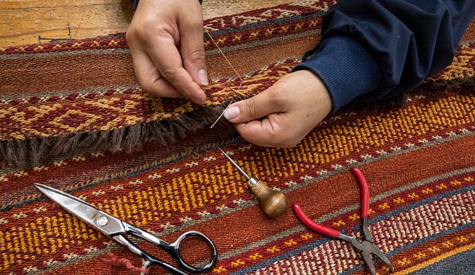 person repairing rug fringe